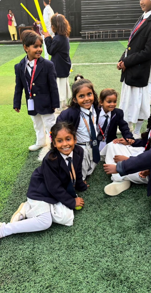 Group of students sitting on the artificial grass turf posing happily